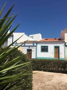 een blauw-wit huis met een palmboom bij Casa Iemanjá in Vila do Bispo