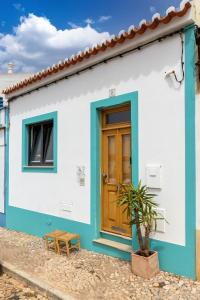 een blauw-wit huis met een houten deur bij Casa Iemanjá in Vila do Bispo