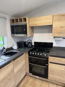 a small kitchen with a stove and a sink at 28 Fentley Green - Ashbourne Heights Holiday Park in Fenny Bentley