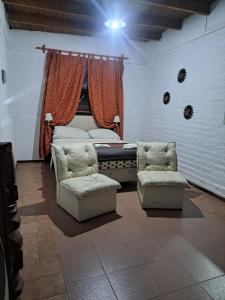 a bedroom with a bed and two chairs in a room at Suspiros De Mendoza in Barraquero
