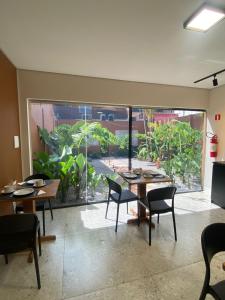 Un comedor con mesas y sillas y un gran ventanal. en Belém Forest Inn, en Belém