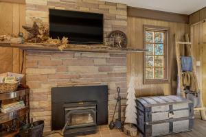a living room with a stone fireplace with a flat screen tv at CrazyHornChalet in Divide +48 photos