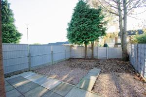 a backyard with a fence and a tree at Ideal Home Away in Whitefield Bury in Manchester
