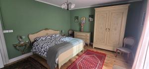 a bedroom with green walls and a bed and a dresser at La Quiete del Mattino in Torre Pellice