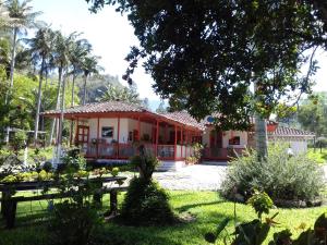 a red house with a garden in front of it at Hostal Rio Arabia - Valle De Cocora HOTEL in Salento