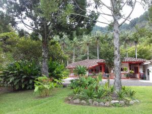 a resort with a red building and some trees at Hostal Rio Arabia - Valle De Cocora HOTEL in Salento