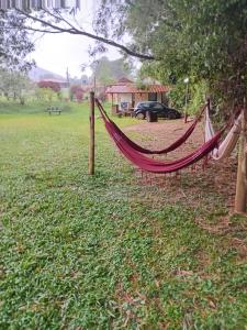 a hammock in a field next to a house at camping elementais in São Thomé das Letras
