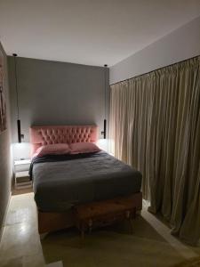 a bedroom with a bed with a pink headboard and curtains at Mimis Skyline in Xanthi