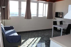 een woonkamer met een bank, een tafel en ramen bij apartamentos la villa in San Sebastián de la Gomera