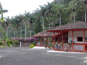 a red and white building with trees in the background at Hostal Rio Arabia - Valle De Cocora HOTEL in Salento +53 photos