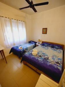een slaapkamer met twee bedden en een plafondventilator bij Hotel Maresias in Villa Gesell