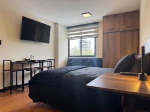 ein Schlafzimmer mit einem Bett und einem Tisch und einem Fernseher in der Unterkunft Black Chic Studio in Cochabamba