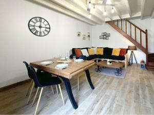 a dining room with a table and a clock on the wall at Le Nid Douillet - Duplex Bois & Charme in Mauléon