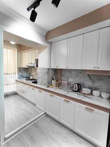 a kitchen with white cabinets and white counters at Апартамент Плаза 3 in Shymkent