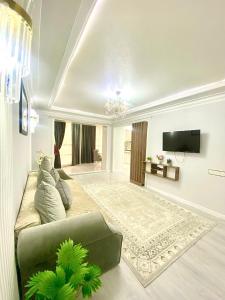 a living room with a couch and a flat screen tv at Апартамент Плаза 3 in Shymkent