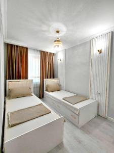 a bedroom with two beds and a chandelier at Апартамент Плаза 3 in Shymkent