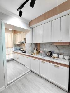 a kitchen with white cabinets and white appliances at Апартамент Плаза 3 in Shymkent