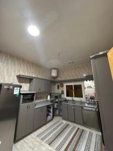 una cucina con elettrodomestici in acciaio inossidabile e armadietti grigi di شقة مدخل خاص بمدخلين a Tanomah