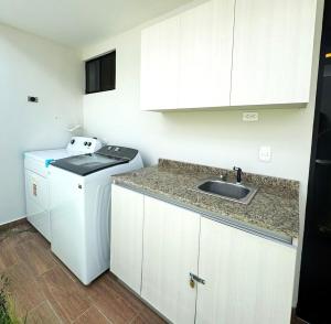 una pequeña cocina blanca con fregadero y lavavajillas en Cozy house 5 minutes from the airport, en Las Flores 9 fotos más