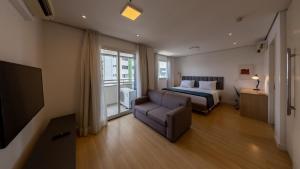 a bedroom with a bed and a couch and a television at St Charbel by Charlie in São Paulo