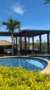 a swimming pool with a palm tree and a gazebo at Casa GERIBÁ in Búzios