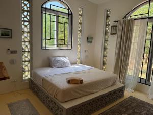 a bedroom with a bed with two windows at Bellerive in Kilifi