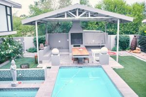 a backyard with a pool and a pavilion with a table and a table at WINDHOEK ODYSSEY House in Windhoek
