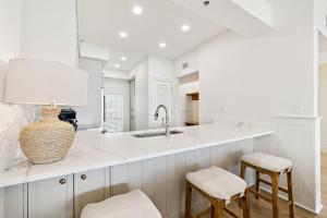 uma cozinha com balcões brancos, um lavatório e bancos em HP 42W Peaceful Nest by 30A Escapes em Rosemary Beach