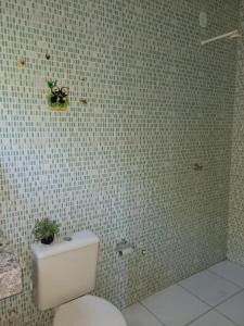 een badkamer met een toilet en een betegelde muur bij Suítes Privativas - Casa Compartilhada in São Raimundo Nonato +15 foto's