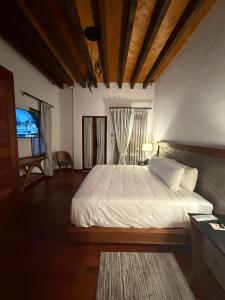een slaapkamer met een wit bed en een televisie bij Mirtala Hotel Boutique in Guanajuato