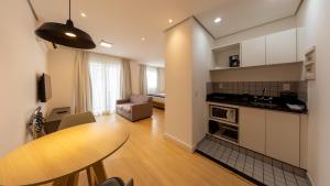 a kitchen and living room with a wooden table in a room at St Charbel by Charlie in São Paulo