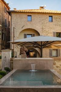 Una fuente frente a un edificio con una sombrilla. en Rastrello, en Panicale