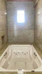 a large white tub in a bathroom with a window at Hotel Concha do Mar in Salinópolis +96 photos