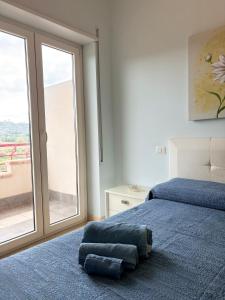 una camera con un letto blu e una grande finestra di La Rocchetta Sunset Apartment a Briatico