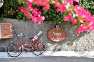 a red bike parked next to a stone wall with a sign at Vagia Traditional, Aegina Island in Vaia