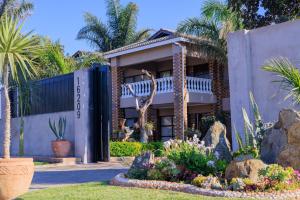 a building with palm trees and plants in a garden at Comfort B&B in Bulawayo