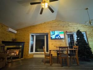 a living room with a table and chairs and a christmas tree at Chalet au bord du lac à la Baie Boudreault in Alma