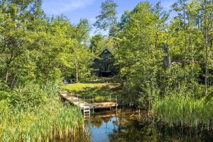 a cabin in the woods next to a lake with a dock at Little Longbow Lakefront Chalet in Becket