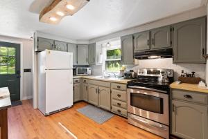 une cuisine avec des armoires grises et un réfrigérateur blanc dans l'établissement Little Longbow Lakefront Chalet, à Becket 40 autres photos