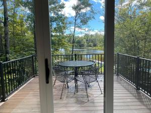 une table et des chaises sur un balcon avec vue sur un lac dans l'établissement Little Longbow Lakefront Chalet, à Becket