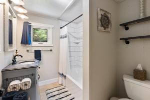 a bathroom with a shower and a sink and a toilet at Little Longbow Lakefront Chalet in Becket +33 photos