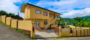 a yellow house with a fence in front of it at Lynette's Palace in Port-of-Spain