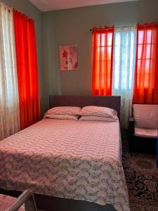 a bedroom with red curtains and a large bed at Lynette's Palace in Port-of-Spain +10 photos