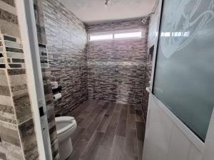 a bathroom with a toilet and a brick wall at departamento 2 en condominio in Amecameca de Juárez