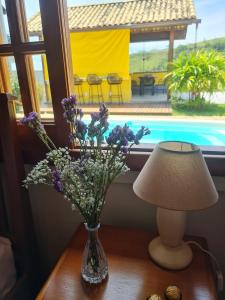 un jarrón de flores sentado en una mesa junto a una lámpara en Refúgios SUNSET Serra Fluminense, en Areal