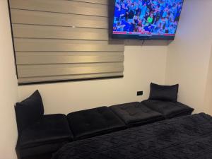 ein schwarzes Sofa in einem Zimmer mit einem Flachbildfernseher in der Unterkunft Superb Loft Park Front in Cochabamba
