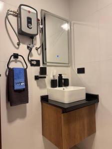 ein Badezimmer mit einem weißen Waschbecken und einem Spiegel in der Unterkunft Superb Loft Park Front in Cochabamba + 8 Fotos