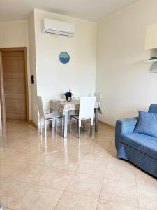 una sala da pranzo con un tavolo e un divano blu di La Rocchetta Sunset Apartment a Briatico
