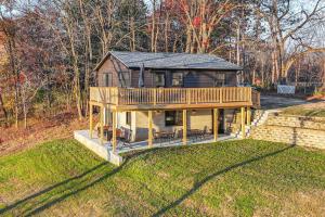 una grande casa con una terrazza in cima a un cortile di Riverfront Reset! Dells Cabin with Kayaks and Deck a Plainville
