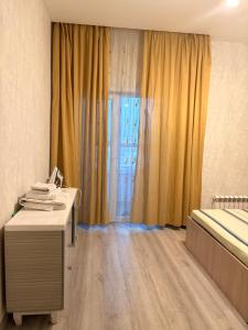 Apple city في Prigorodnyy: غرفة بها سرير ومكتب ونافذة